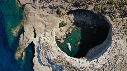 Aerial drone photo of beautiful volcanic open cave of Sykia a geological phenomenon - leaving an opening for small boat to enter in South West of Milos island, Cyclades, Greece