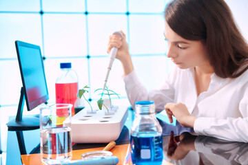 Young woman with a pipette in a plant laboratory. Study of the effect of fertilizers and growth accelerators on plants