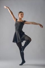 a dancer, on a grey background. A dancing woman. The ballerina stands at full height.