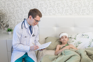 Fototapeta premium The pediatrician is at the appointment of a sick child. A boy with a thermometer, temperature. The doctor records the result of the examination in a notebook
