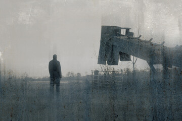 A bleak, moody, winters day of a male figure standing next to quarry machinery in a field in the countryside. With a blurred, textured, weathered, abstract sepia edit.