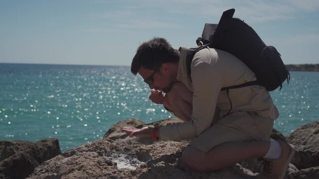 Male geologist examines samples of crystals sea salt from the rocks near sea. Marine geologist examines mineral sample evaporated from the sea on a rocky area. Geology researcher looking for samples.