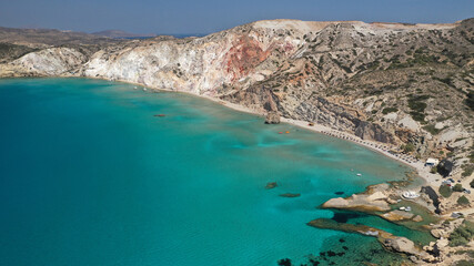 Aerial drone view of iconic volcanic white chalk sandy organised with sun beds and umbrellas beach of Firiplaka with turquoise clear sea and rocky colour formations, Milos island, Cyclades, Greece