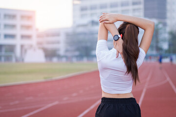 A young beautiful Asian woman in sports outfits doing stretching before workout outdoor in the park in the morning to get a healthy lifestyle. Healthy young woman warming up outdoors