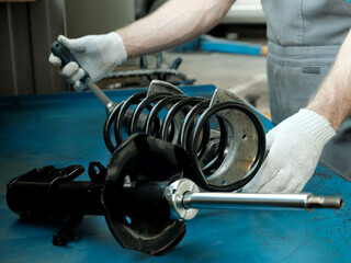 Car spare parts.The mechanic performs the work of replacing the spring and shock absorber of the...