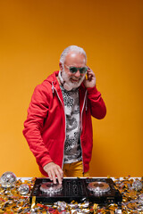 Stylish man in street style outfit works with dj controller. Happy adult guy with grey beard in red...