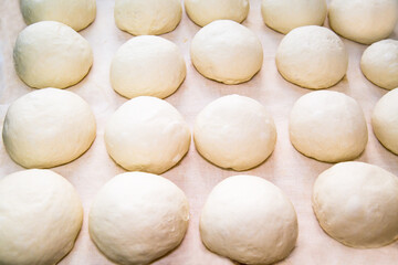 Fototapeta na wymiar Lumps of dough on a white board, prepared for making and baking Uzbek tortillas. Confectionery products national traditional dishes and pastries.