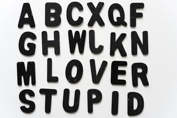alphabet arranged with cryptic message (lover stupid) in black chalk letters on a white background