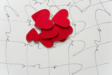 pile of hand painted wooden red hearts on a paper background with the word, love, written multiple times