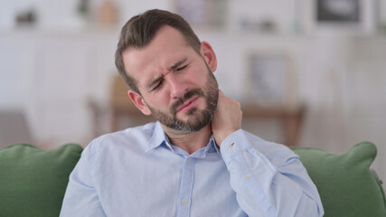 Naklejka premium Young Man with Neck Pain at Home 