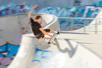 Jugendlicher Skater im Skate Park auf der Halfpipe: Zoom - Sprung / Slide an der Kante