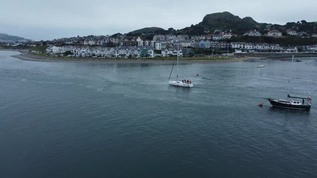 Aerial dolly left view yacht navigating seaside mountain Welsh town quiet river Conwy estuary