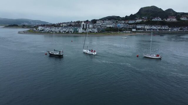 Aerial tracking left view yacht navigating seaside mountain Welsh town quiet river Conwy estuary