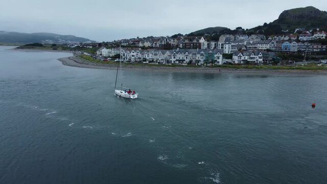 Aerial view travelling sailboat cruising misty mountain bay navigating quiet river Conwy seaside town tracking left