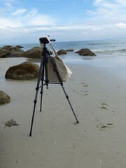 Camera with tripod and white cloth bag on the beach