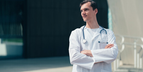 tired young doctor standing near the entrance to the hospital .