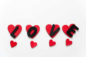 the letters l, o, v, and e on hand painted red hearts isolated on a white paper background