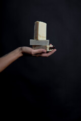 Female hands holding natural three cosmetics soap bars with copy space in a black background.