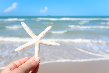 Fototapeta na wymiar Hand holding starfish with beautiful tropical summer sand beach island, relaxing vacation summer blue sea concept