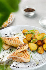 grilled chicken steak with potatoe idaho on ceramic plate with ingredients on concrete table