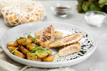 grilled chicken steak with potatoe idaho on ceramic plate with ingredients on concrete table
