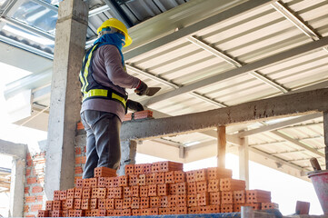 Builder carefully puts red brick on the masonry. Quick work bricklayer. Guy measures level masonry. Man is building brick wall. Correctly calculate material. Builder manually carries brick structure