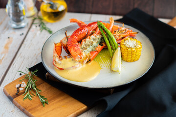 Grilled canadian lobster with grilled asparagus baby corn and sabayon sauce on wooden board