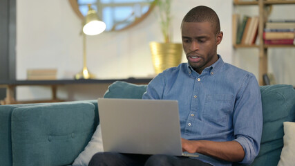 Tense Young African Man Working on Laptop 
