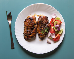Chicken grilled steak and vegetables in a white plate on a wooden background with use of selective focus