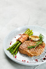grilled pork steak with asparagus and rosemary leaf on concrete table close up