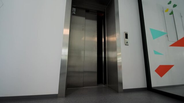 The doors of the office elevator close. The passenger elevator is empty without people.