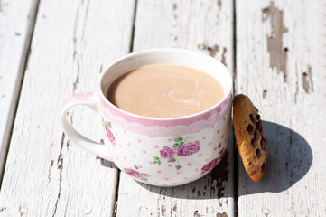 Coffee cup with milk on peeling white wood