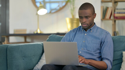 Beautiful Young African Man using Laptop on Sofa 