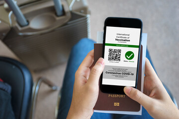 Disease immunity passport, Tourist uses of application on smartphone to show an international certification of vaccination at airport with Immunity passport and vaccination record card for covid-19
