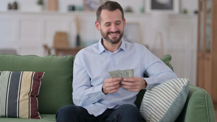 Successful Young Man Counting Dollar at Home