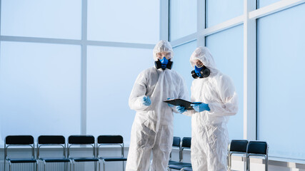 lab technicians in protective suits discussing the work plan.