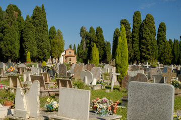 View of tombstone and cypresses threes inside venetian cemetery of San Michele island, Venice, Italy