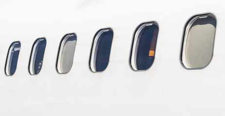 Fuselage of a white aircraft with windows, seen from outside.