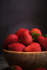 strawberries in a wooden bowl on a gray background