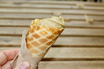 Holding in hand a natural pistachio gelato in a cone (cornet)
