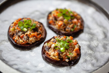 Eggplants baked with vegetables on a black plate