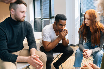 Close-up of depressed African American young man sharing problem sitting in circle on group therapy session. Concept of group consulting of mental health problem with professional psychologist.