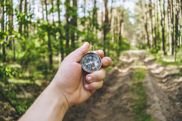 Compass in a guy s hand on the background of the forest. Concept on the theme of tourism.