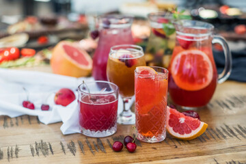 A composition of glass decanters and glasses with refreshing soft drinks made from fruits and berries.