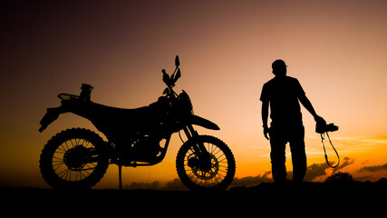 Silhouette photographer adventures with a motorcycle off-road or motocross in the evening. travel...