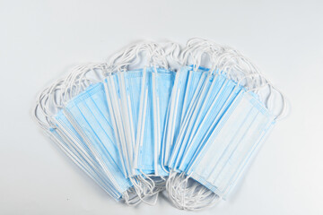medicine, healthcare and pharmacy concept - many blue disposable medical masks on a white background. Copyspace. Flatlay