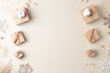 Christmas decorations with packaging gifts in craft paper and flowers on beige background. Zero waste Christmas holiday concept. Flat lay, copy space