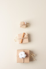 Christmas minimal composition with packaging gifts in craft paper and flowers on beige background. Flat lay, copy space