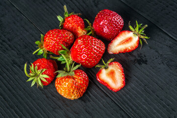 A lot of red ripe strawberries on black vintage table. Summer diet and vitamin set idea