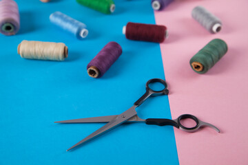 Colorful threads and scissors  isolated on pink and blue backgrounds.